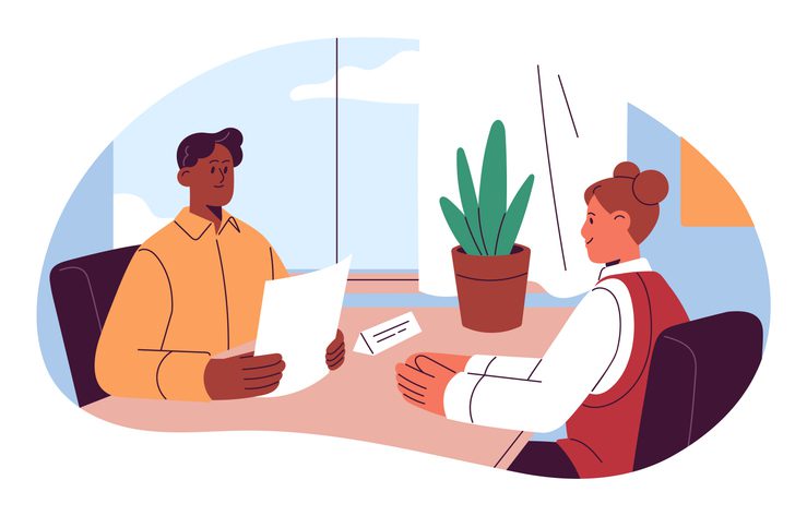 Two people seated at a table in an office, one presenting a paper while the other listens, with a potted plant and window in the background.