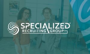 Two professionals standing in an office with the Specialized Recruiting Group logo prominently displayed in the foreground. Text in image says "Specialized Recruiting Group."