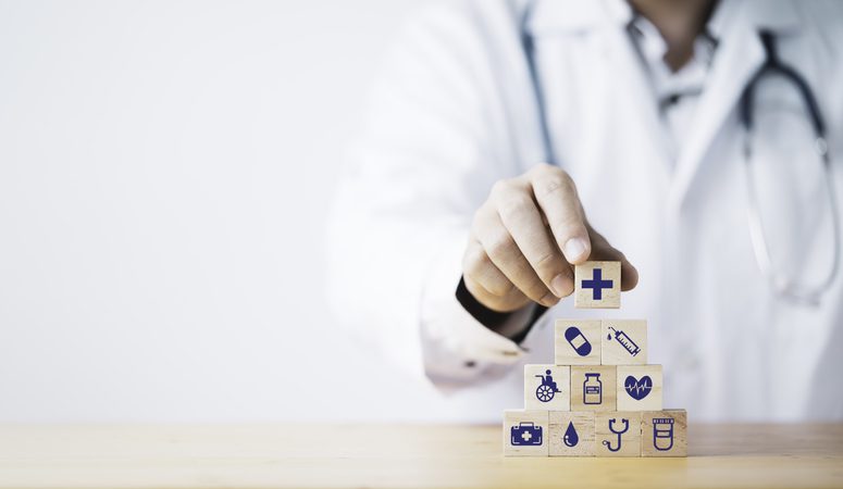 Medical professional stacking wooden blocks with medical icons.