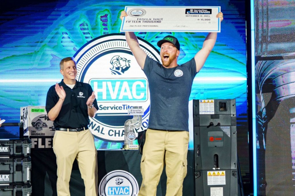 Two individuals on stage at the HVAC ServiceTitan National Championship; one holds a $15,000 check while the other claps, with FLEX equipment visible.