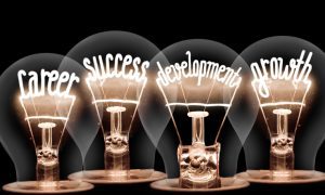 Photo of light bulb with shining fibers in shapes of CAREER , SUCCESS, DEVELOPMENT, GROWTH concept words isolated on black background