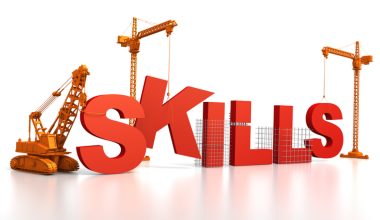 Illustration of the word “SKILLS” in large red 3D letters being constructed by three orange construction cranes and a bulldozer on a white background.