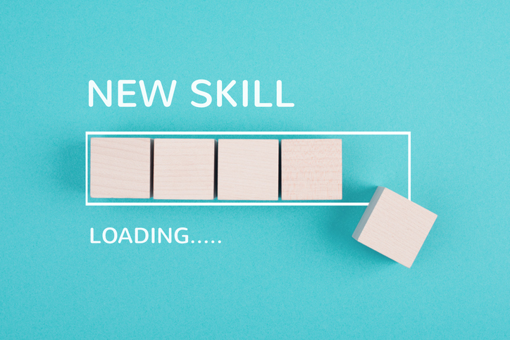 Photo of a teal background with wooden blocks arranged like a progress bar and one block offset to the right, with white text reading “NEW SKILL” above and “LOADING…..” below.
